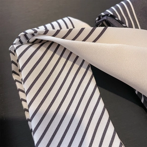 Detailed macro shot of French style black and white diagonal striped silk neck scarf texture