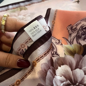 Detail of a 100% real silk square scarf showing the label and floral chain pattern