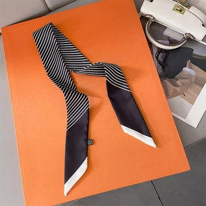 Close-up of black and white striped twilly silk scarf on orange backdrop with handbag