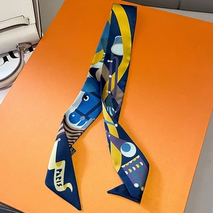 Detail eines schmalen Seidenschals mit Pferdemuster und PARIS-Text auf orangefarbener Box