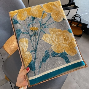 Thick winter scarf with yellow floral print on grey background shown by hand