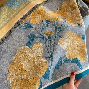 Detailed close-up of retro floral woven scarf featuring blue roses and gray fringe trim