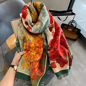 Thick autumn scarf with red maple leaf print and fringe on a grey leather chair