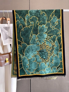 Close-up of luxury velvet winter scarf with floral pattern and tassels hanging in closet