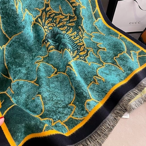 Detailed close-up of peacock green and gold floral cashmere scarf with soft grey fringe
