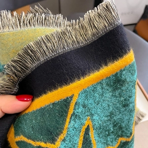 Close-up of thick winter scarf texture showing green and yellow pattern with soft fringes