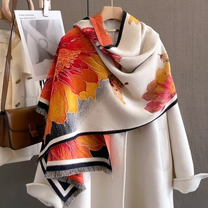 Thick floral cashmere shawl with orange flower print and tassel trim on white coat