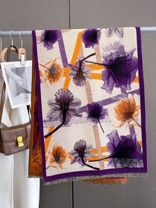 Detail of purple floral scarf with tassels hung next to a white coat and brown leather bag