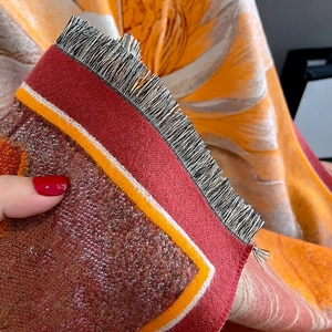 Close-up of thick knitted scarf texture featuring orange patterns and fine black fringes
