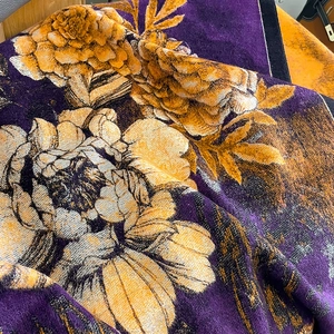 Close-up of thick winter scarf featuring purple fabric with large yellow floral jacquard