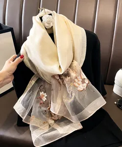 Detailed embroidery of flowers on beige silk wool scarf with machine hemmed edges
