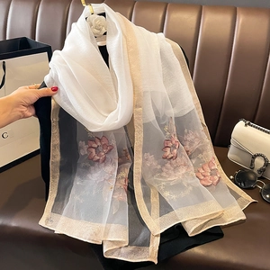 Détail de l'écharpe en soie et laine blanche avec broderies florales roses et bord doré