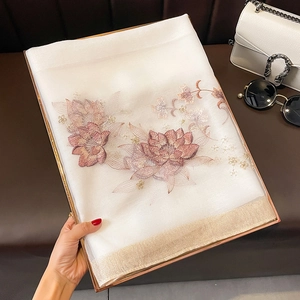Détail de la broderie florale sur un châle en soie et laine blanc aux bords dorés