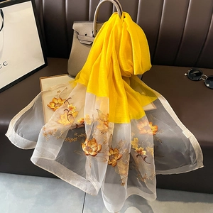 Détail d'une écharpe en soie et laine jaune avec broderie florale sur voile