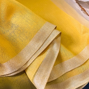 Détail de l'écharpe en soie et laine jaune avec bordure dorée scintillante et texture