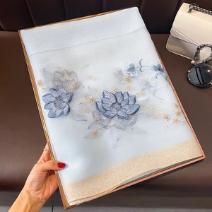 Détail de l'écharpe en soie et laine bleu clair avec broderie lotus et bord doré brillant