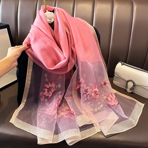 Gros plan de l'écharpe en soie et laine rose avec broderies florales et bordure dorée