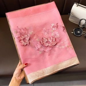 Détail de la broderie de lotus sur châle en soie et laine rose avec bord doré