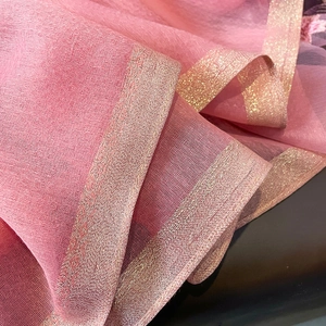 Détail macro d'une écharpe en soie et laine rose avec bordure brodée pailletée or rose