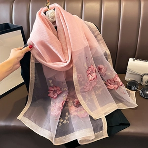 Détail d'une écharpe en soie et laine rose avec broderie florale et liseré doré