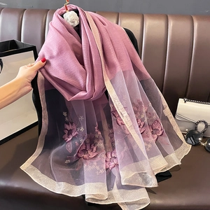 Détail d'une écharpe en soie avec broderie florale violette et bordures métallisées