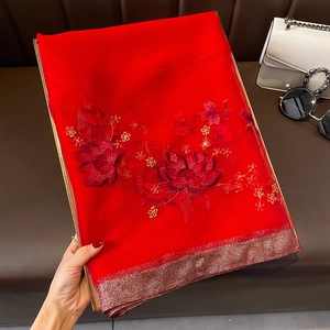 Gros plan d'une écharpe élégante en soie et laine rouge avec broderie florale et bord doré