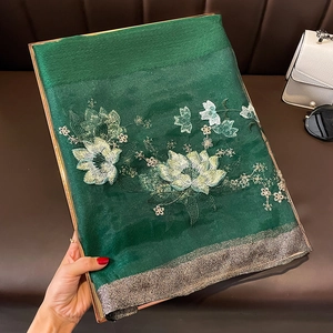 Détail du châle en soie et laine vert foncé avec broderie florale et bordure dorée