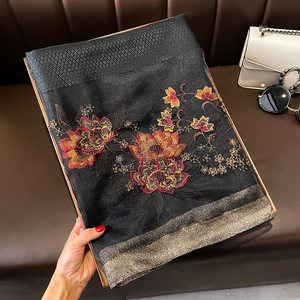 Détail de la broderie florale sur un châle noir en mélange de soie et laine