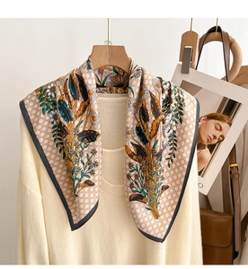 Close-up of checkerboard scarf with daisy and feather patterns on a beige knit sweater