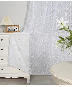 Detail of white lace sheer curtain with damascus floral pattern in a cozy room