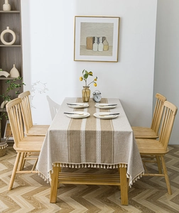 Detailed close-up of Nordic striped tablecloth with white decorative tassels on wood table