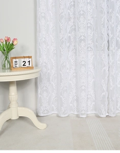 Detail of white lace curtain featuring baroque damask patterns and elegant scalloped edges