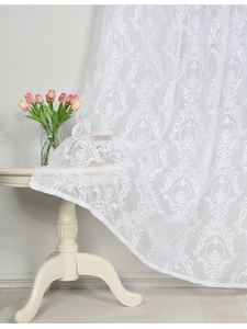 Detail of white lace curtain featuring damask floral embroidery on a translucent fabric