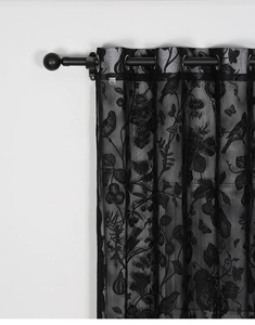 Detail of black grommet lace curtain with floral and bird pattern on white background