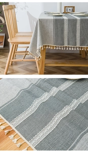 Detail of Nordic grey-green striped tablecloth with cotton-linen texture and white tassels