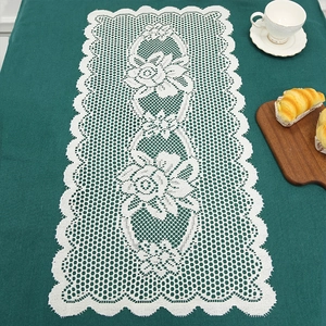 Nordic white lace table runner with rose patterns on a dark green surface