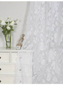 Detail of white lace sheer curtain featuring intricate floral and bird embroidery patterns