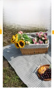 Classic black and white checkered picnic mat on lawn with flowers and fruit basket