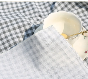 Detail of bohemian white textured fabric with tassel edges on checkered picnic mat