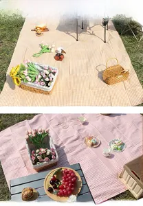 Detailed view of yellow and pink plaid outdoor picnic mats on green grass