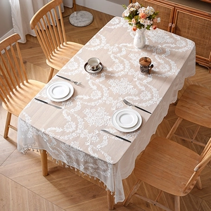 French retro beige lace tablecloth with floral patterns and fringe on a wooden table