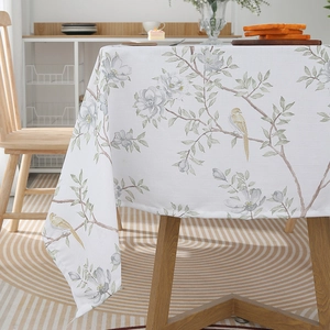 Detailed view of Nordic style tablecloth featuring green leaves and yellow birds prints