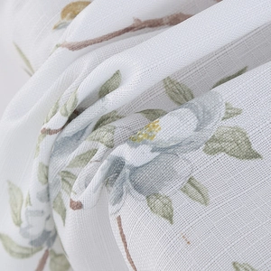 Detailed close-up of faux linen fabric with Nordic green leaves and blue floral prints