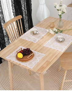 Detailed view of white rectangular lace placemats with floral and butterfly patterns