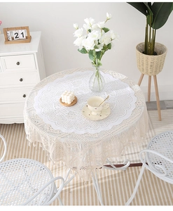 Detailed macro view of cream lace tablecloth with hollow patterns and fringe tassels