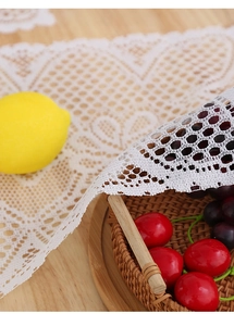 Detailed view of white floral lace table runner with intricate hollow mesh patterns