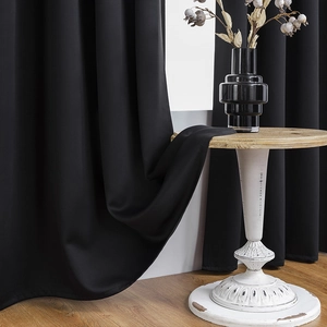 Detail of heavy black blackout curtain fabric with elegant drape for bedroom use