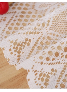 Detailed view of white lace table mat with intricate hollow mesh and wavy edges