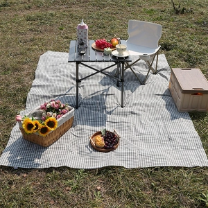 Outdoor picnic blanket with black and white checkered pattern on a natural lawn