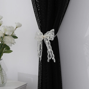 Elegante alzapaños de encaje blanco con lazo y perla sobre cortina oscura